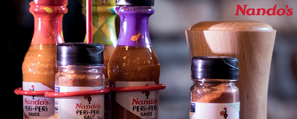 A range of Nando's Peri Peri sauce gift bottles with dips, crisps and olives.